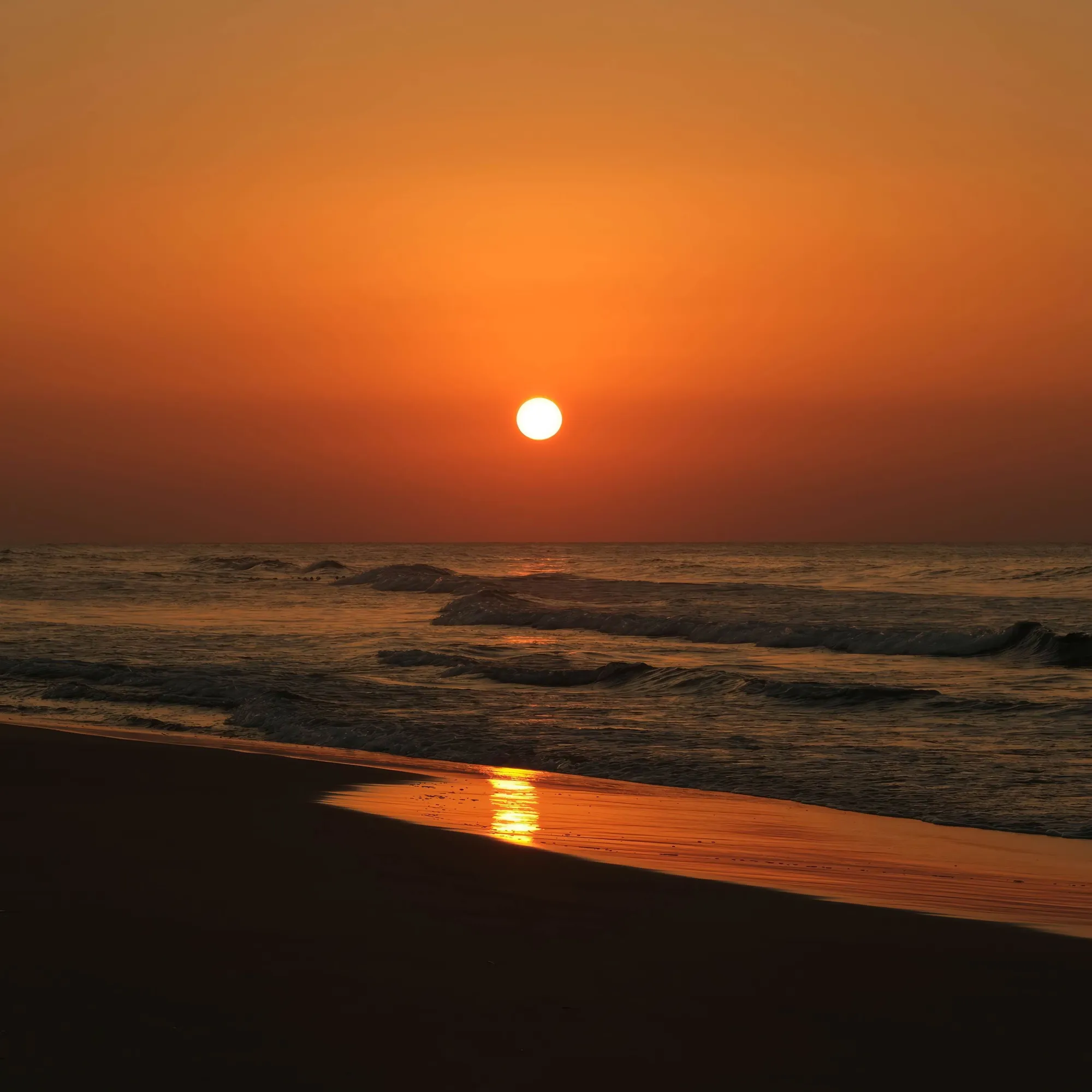 Cover artwork for Oceans Apart: a low orange sun over the sea, its reflection running across wet sand at dusk.